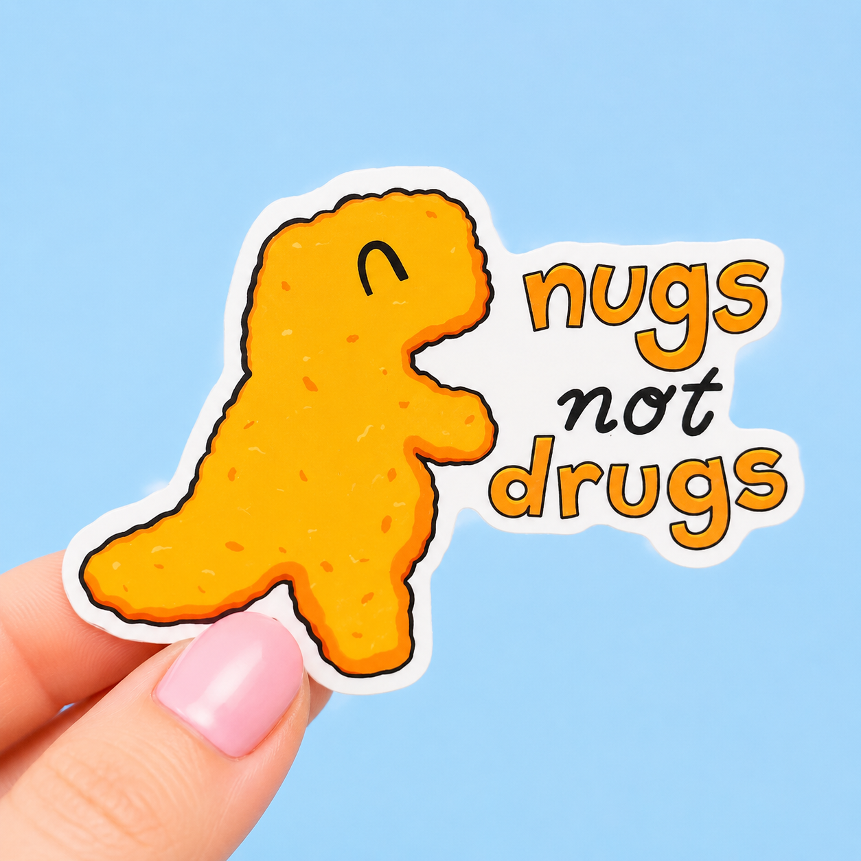 Sleazy Greetings funny vinyl sticker featuring a dinosaur-shaped chicken nugget beside the phrase ‘Nugs Not Drugs.’ Cute die-cut food humor sticker with playful typography, golden nugget illustration, and trendy kawaii aesthetic.