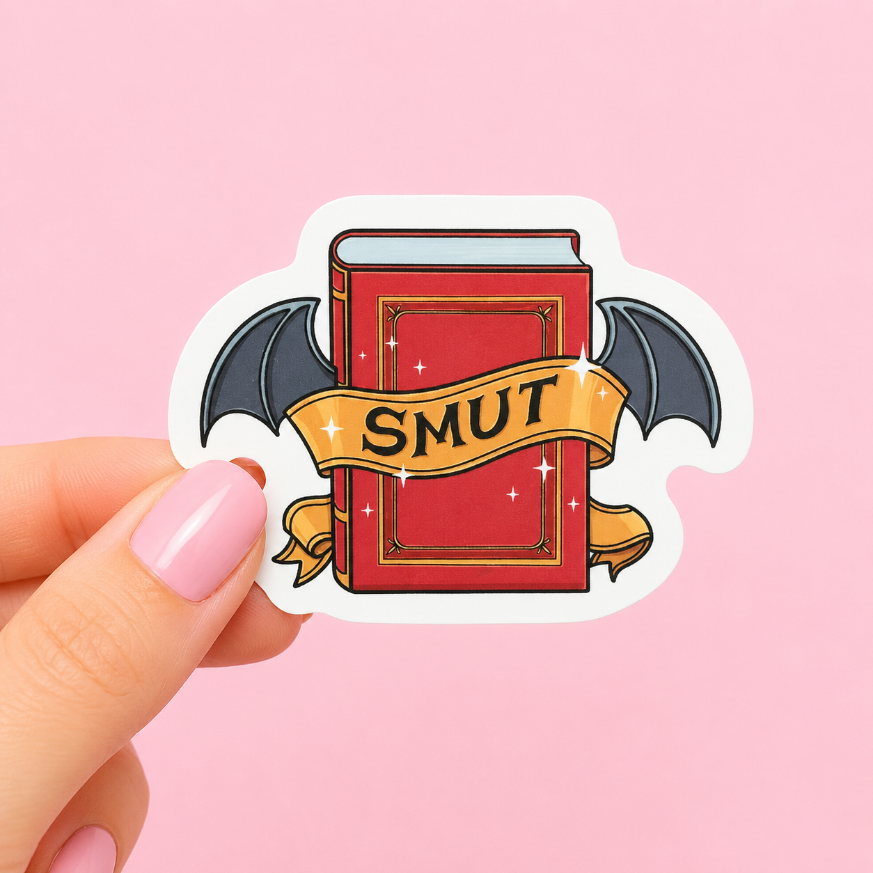Sleazy Greetings funny die-cut vinyl sticker featuring a mysterious red spellbook with bat wings and a banner that says ‘Smut.’ Cute gothic book-lover sticker with spicy reader humor, magical fantasy aesthetics, and chaotic morally-gray bookworm energy.