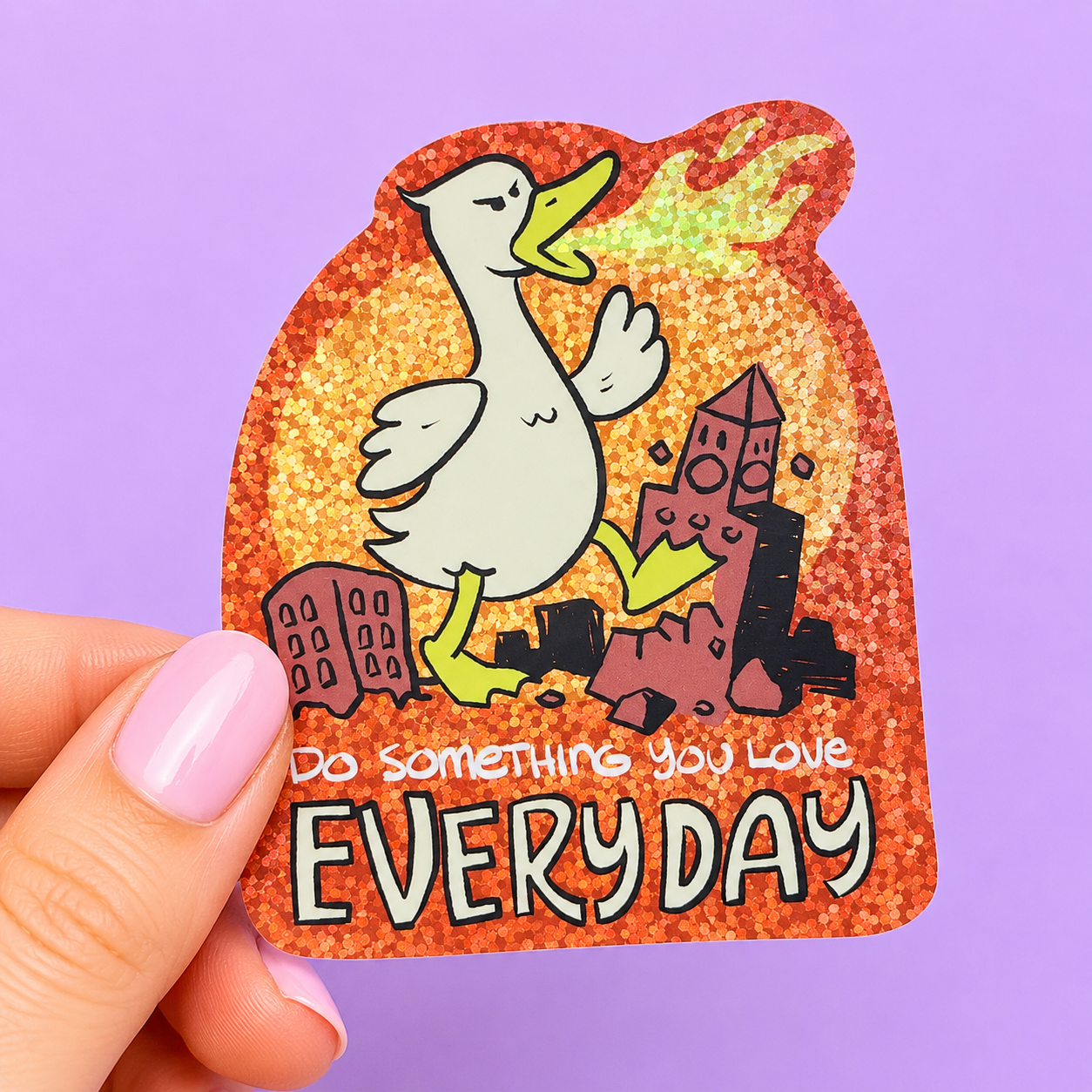 Sleazy Greetings funny die-cut vinyl sticker featuring a giant fire-breathing goose stomping through a collapsing city beside the phrase ‘Do Something You Love Every Day.’ Chaotic silly goose sticker with monster movie parody vibes, glittery fiery background, and absurd destructive humor aesthetic.