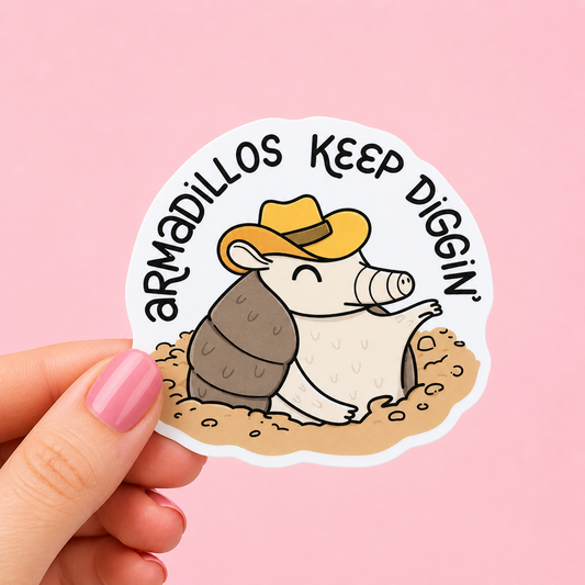 Sleazy Greetings funny die-cut vinyl sticker featuring a happy little armadillo in a cowboy hat beside the phrase ‘Armadillos Keep Diggin’.’ Cute chaotic southern-style sticker with playful cartoon artwork, wholesome gremlin energy, and determined little trash-animal vibes.