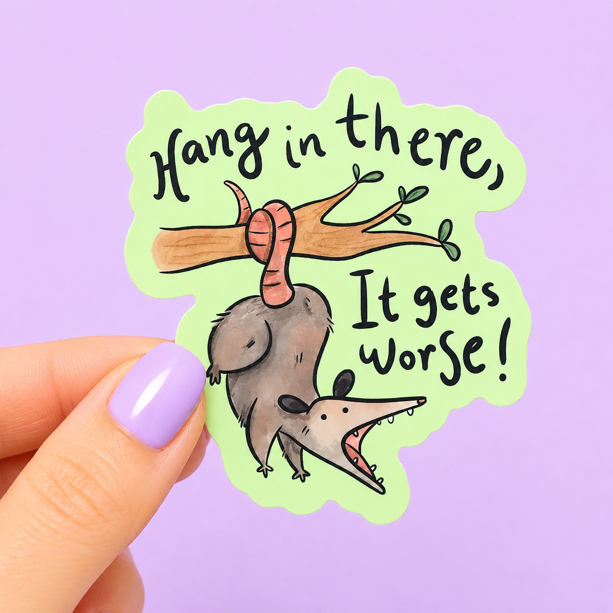 Sleazy Greetings funny die-cut vinyl sticker featuring an upside-down possum hanging from a tree branch beside the phrase ‘Hang in There, It Gets Worse!’ Cute chaotic possum sticker with sarcastic encouragement humor, whimsical watercolor-style artwork, and emotionally exhausted trash-animal energy.