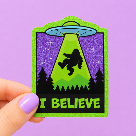 Sleazy Greetings funny holographic vinyl sticker featuring Bigfoot being abducted by a UFO above a forest beside the phrase ‘I Believe.’ Glittery cryptid sticker with retro alien artwork, paranormal humor, and playful spooky aesthetic.