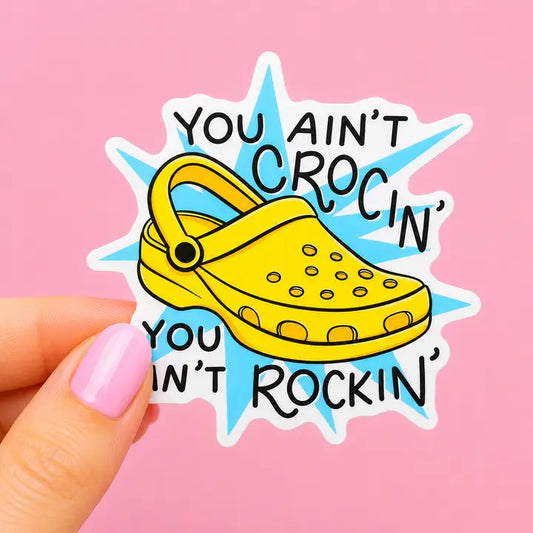 Sleazy Greetings funny Crocs vinyl sticker reading "You Ain't Crocin' You Ain't Rockin'" featuring a yellow clog illustration on waterproof die cut vinyl
