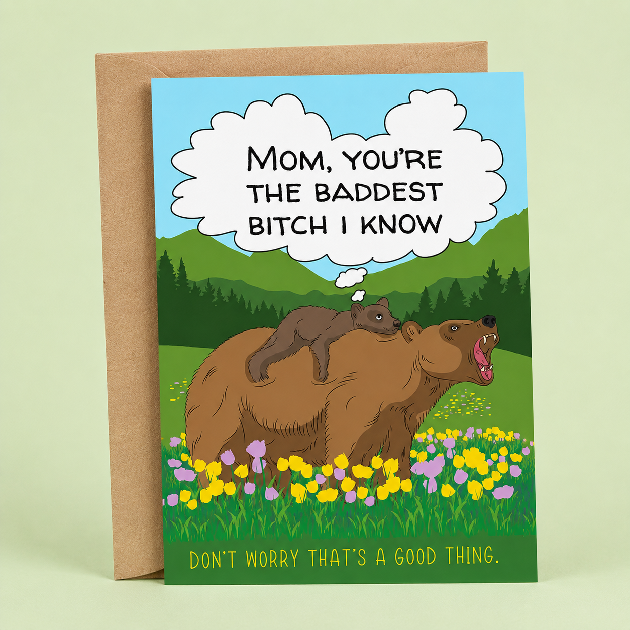 Sleazy Greetings funny Mother’s Day card featuring a mama bear carrying her cub through a colorful wildflower meadow with mountains in the background. The card reads, “Mom, You’re the Baddest Bitch I Know,” followed by, “Don’t Worry That’s a Good Thing,” creating a humorous and empowering Mother’s Day message. Displayed with a kraft envelope, this funny card is perfect for moms with a strong personality, great sense of humor, and fierce protective instincts.