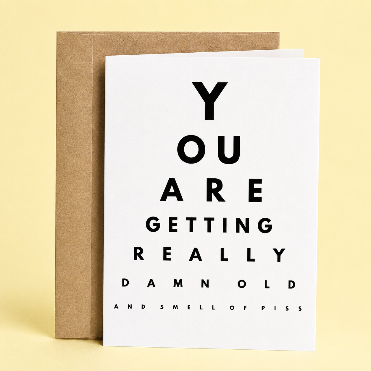 Sleazy Greetings funny birthday card designed like an eye chart on a clean white background. The oversized letters spell out, “You Are Getting Really Damn Old,” with the smallest line humorously reading, “And Smell of Piss.” Displayed with a kraft envelope, this sarcastic aging birthday card is perfect for friends, coworkers, siblings, husbands, wives, parents, or anyone with a dark sense of humor about getting older.