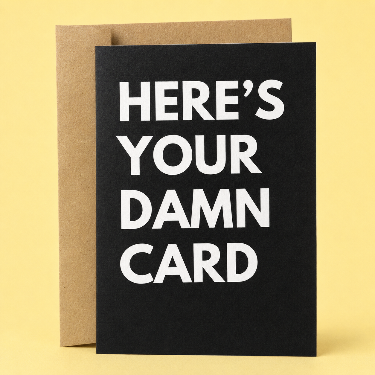 Sleazy Greetings funny minimalist greeting card featuring bold white typography on a solid black background that reads, “Here’s Your Damn Card.” A sarcastic and straightforward card perfect for birthdays, celebrations, or any occasion when you just need to hand over a card. Displayed with a kraft envelope against a soft yellow background.
