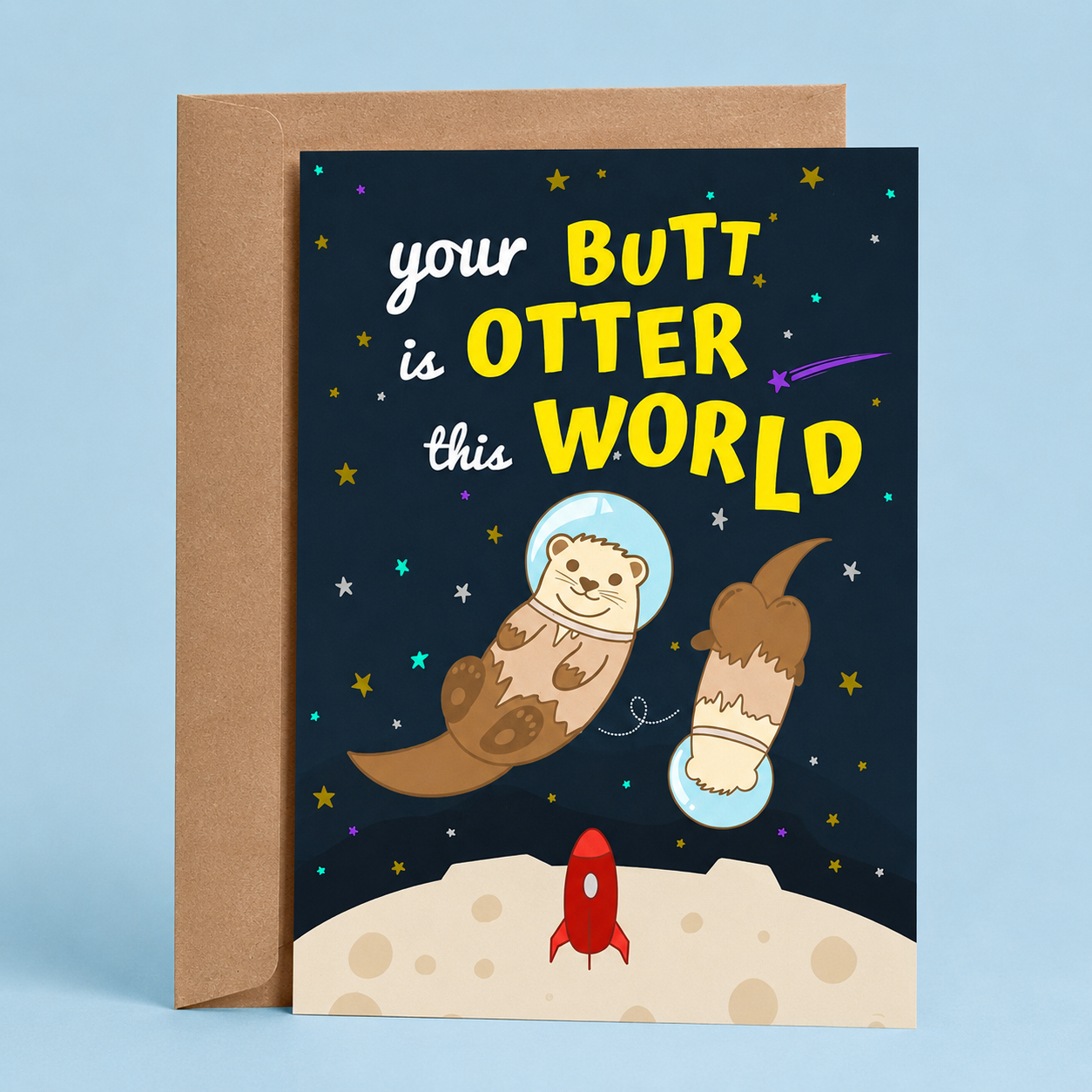 Sleazy Greetings funny love card featuring two adorable otters floating in outer space wearing astronaut helmets above a moon surface. The card reads, “Your Butt Is Otter This World,” making a playful otter pun and compliment, and is displayed with a kraft envelope.