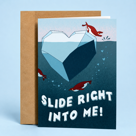 Sleazy Greetings funny love greeting card featuring playful penguins swimming around a heart-shaped iceberg with the romantic pun “Slide Right Into Me!” on a blue ocean background, displayed with a kraft envelope for an anniversary, Valentine’s Day, wedding, boyfriend, girlfriend, husband, wife, or penguin lover greeting card.