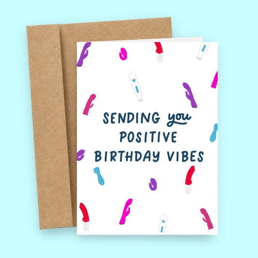 Sleazy Greetings funny adult birthday greeting card featuring colorful vibrator and adult toy illustrations scattered across a white background with the cheeky message “Sending You Positive Birthday Vibes,” displayed with a kraft envelope for a humorous birthday card, gag gift, best friend card, or adult novelty greeting card.