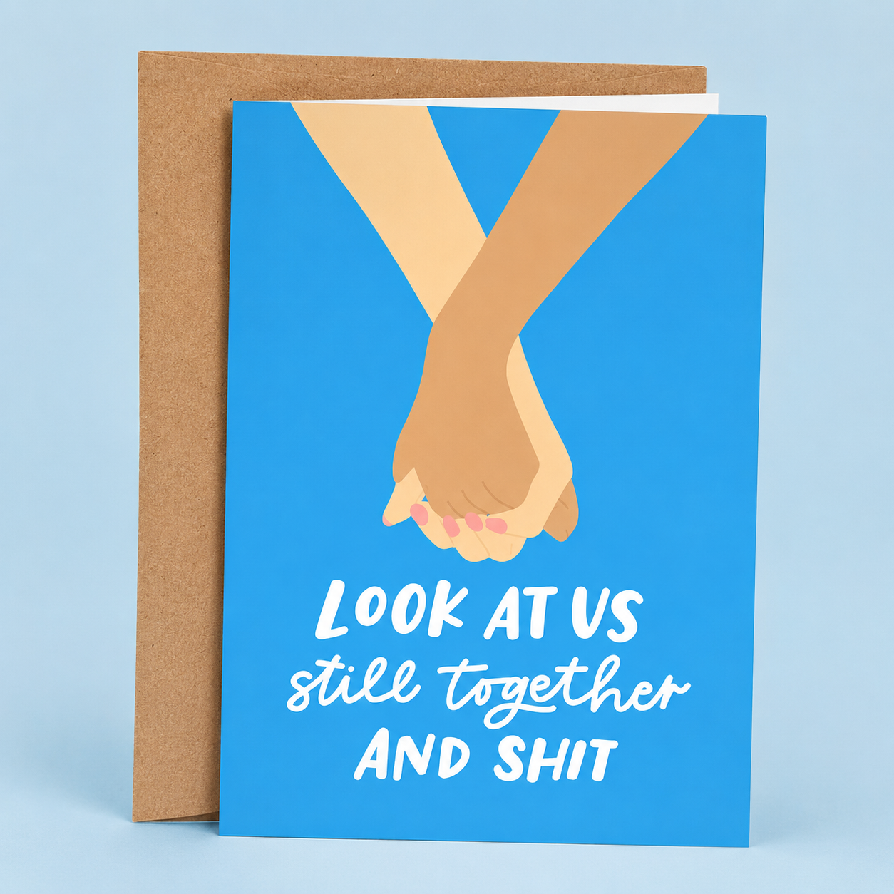 Sleazy Greetings funny love greeting card featuring two people holding hands on a bright blue background with the sarcastic romantic message “Look at Us Still Together and Shit,” displayed with a kraft envelope for an anniversary, Valentine’s Day, wedding, boyfriend, girlfriend, husband, or wife card.