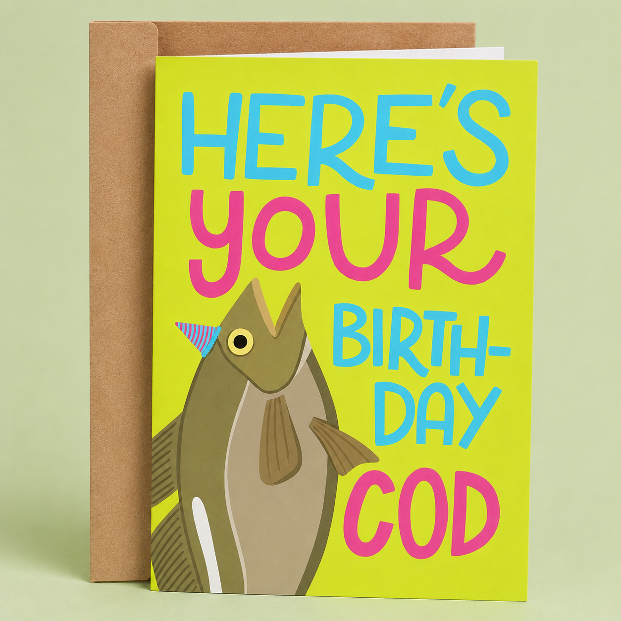 Sleazy Greetings funny birthday card featuring a fish wearing a party hat on a bright lime green background. The card reads, “Here’s Your Birth-Day Cod,” making a playful fish pun birthday joke, and is displayed with a kraft envelope.
