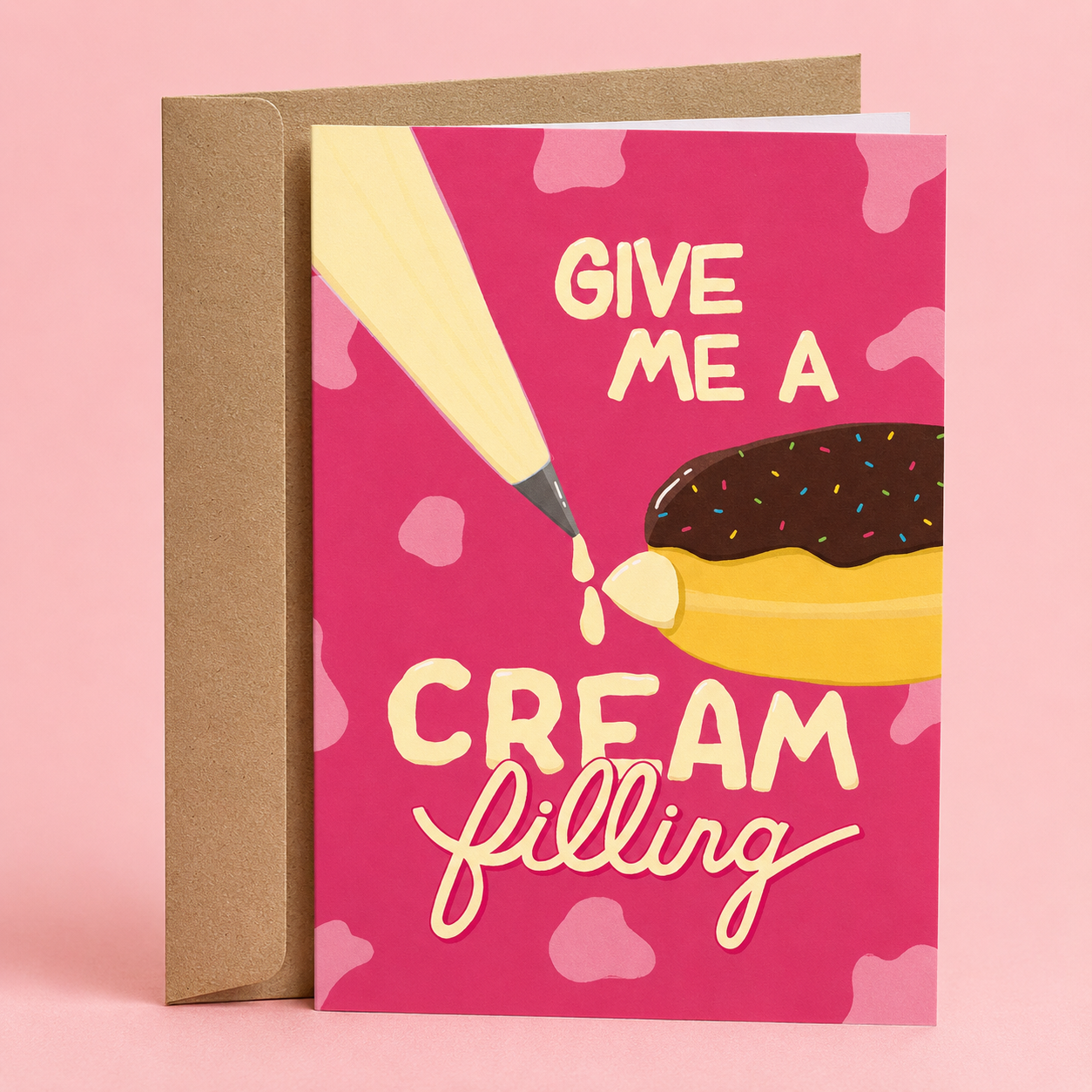 Sleazy Greetings funny adult birthday card featuring a cream-filled chocolate donut and a pencil on a bright pink background. The card reads, “Give Me a Cream Filling,” making a cheeky bakery-inspired innuendo, and is displayed with a kraft envelope.