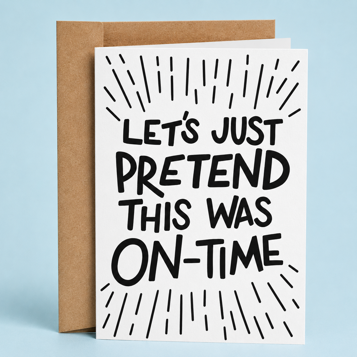 Sleazy Greetings funny belated card featuring bold black typography on a white background with decorative burst lines surrounding the message, “Let’s Just Pretend This Was On-Time.” Displayed with a kraft envelope.