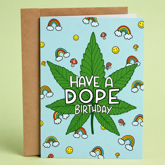 Sleazy Greetings funny cannabis birthday card featuring a large marijuana leaf on a light blue background surrounded by rainbows, smiley faces, and mushrooms. The card reads, “Have a Dope Birthday,” and is displayed with a kraft envelope.