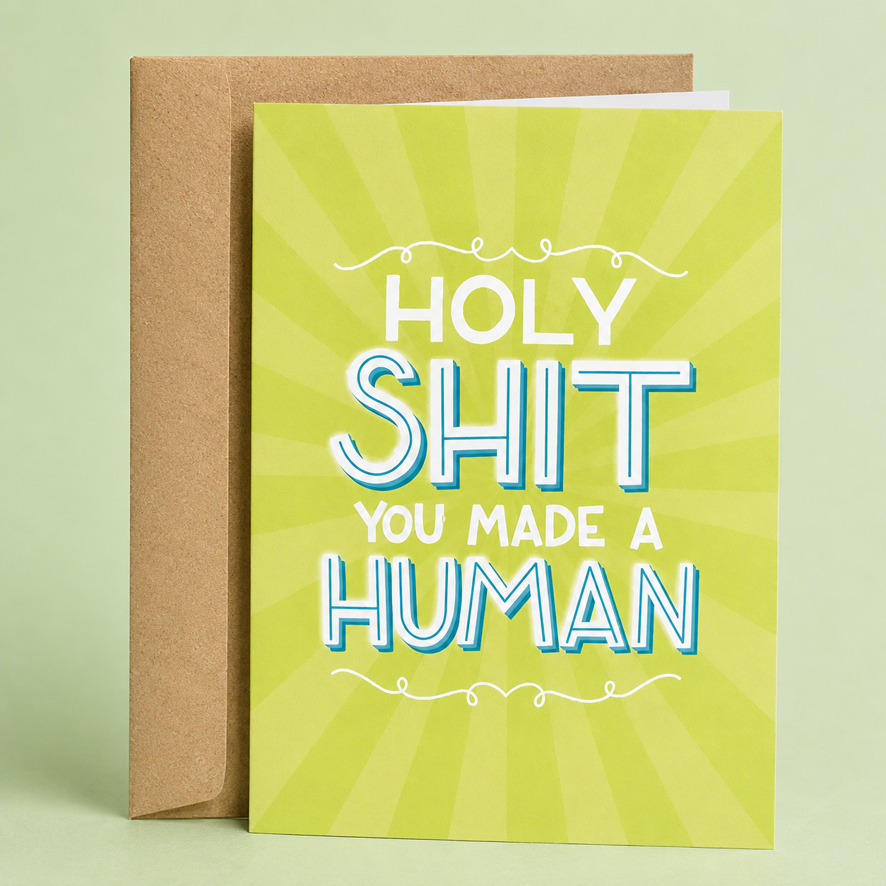 Sleazy Greetings funny new baby card featuring a bright green sunburst background with bold retro lettering, with the humorous congratulatory message “Holy Shit You Made a Human,” paired with a kraft envelope.