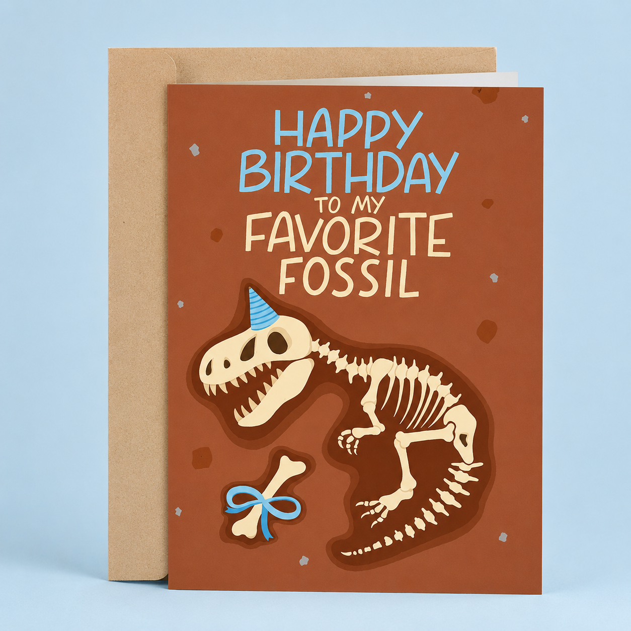 Sleazy Greetings funny birthday card featuring a dinosaur fossil skeleton wearing a party hat on a brown excavation-style background, with the age-related joke “Happy Birthday To My Favorite Fossil,” paired with a kraft envelope.