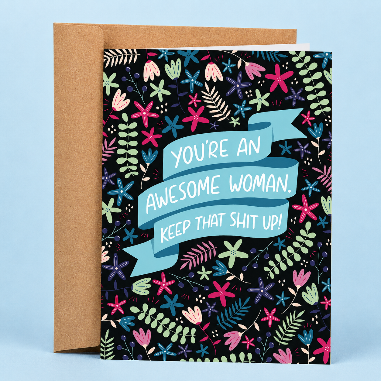 Sleazy Greetings inspirational friendship and encouragement card featuring a colorful floral pattern on a black background with a blue ribbon banner that reads “You’re An Awesome Woman. Keep That Shit Up!” paired with a kraft envelope.