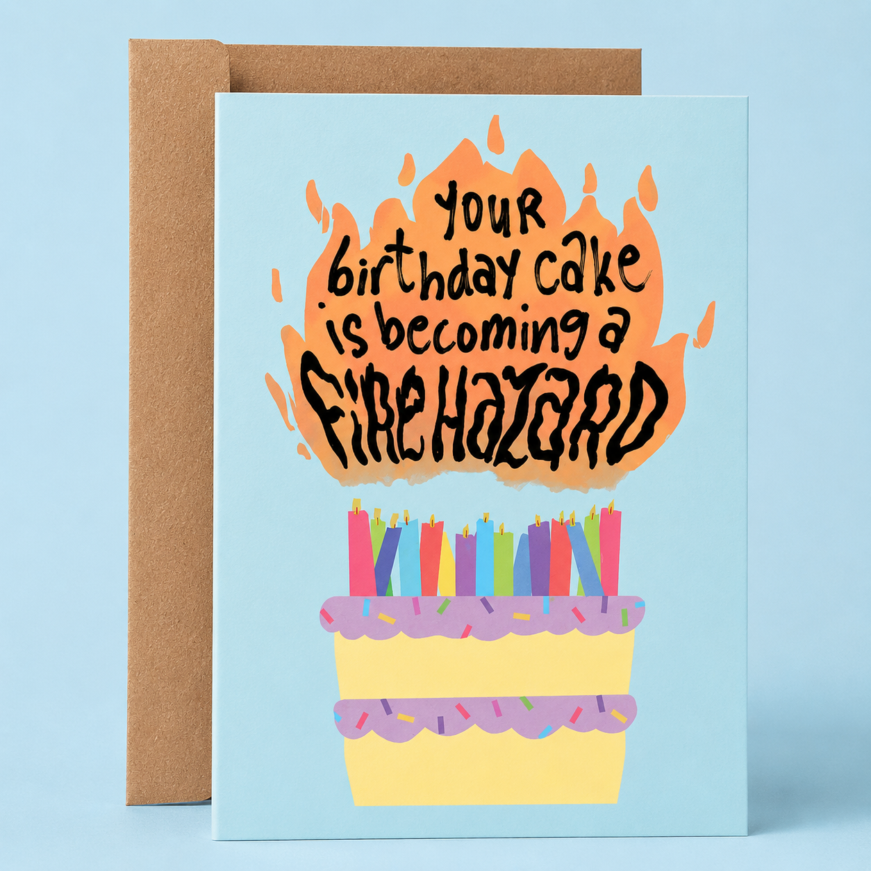 Sleazy Greetings funny birthday greeting card featuring a birthday cake covered in candles and flames on a light blue background with the joke “Your Birthday Cake Is Becoming A Fire Hazard,” paired with a kraft envelope.