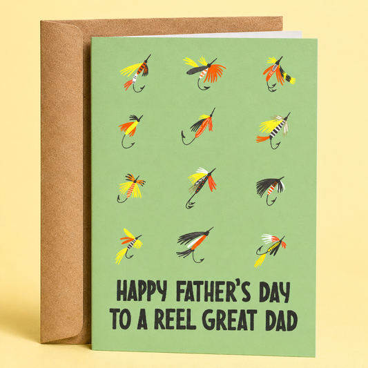 Sleazy Greetings funny Father’s Day greeting card featuring a collection of colorful fly fishing flies on a light green background with the pun “Happy Father’s Day To A Reel Great Dad,” paired with a kraft envelope.