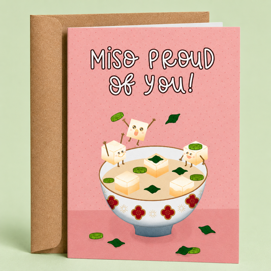 Sleazy Greetings funny graduation congratulations card featuring happy cubes of tofu jumping in a bowl of miso soup on a pink background with the pun “Miso Proud Of You!” paired with a kraft envelope.