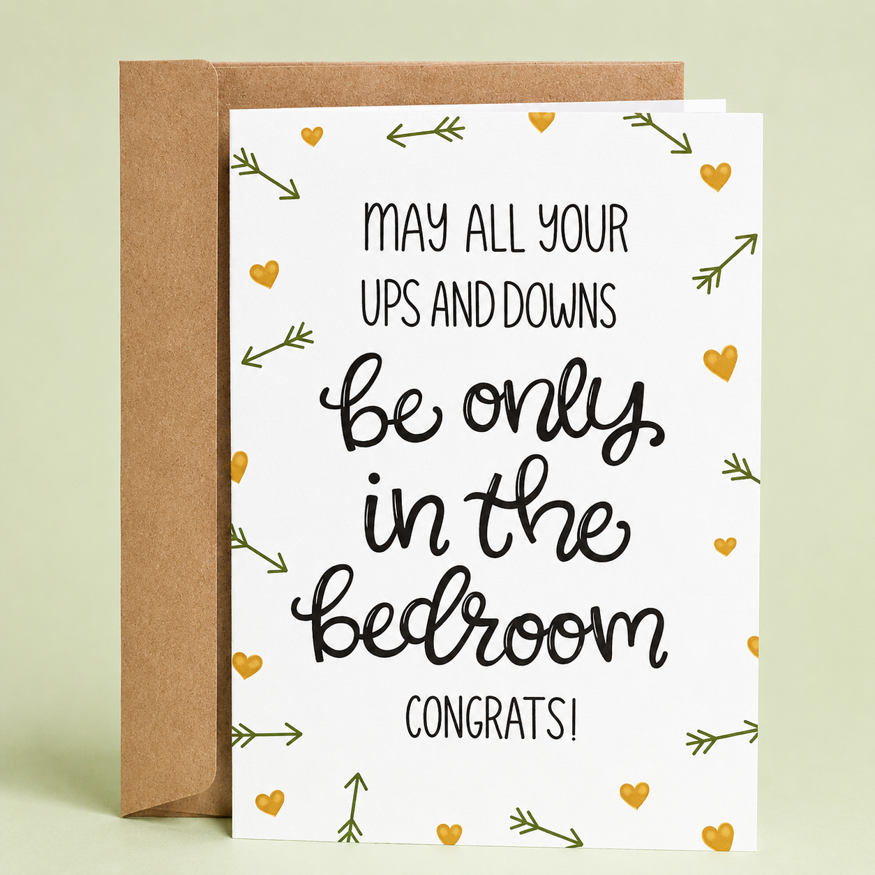 Sleazy Greetings funny wedding and engagement congratulations card featuring elegant typography on a white background with hearts and arrows that reads “May All Your Ups And Downs Be Only In The Bedroom. Congrats!” paired with a kraft envelope.