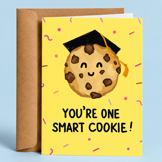 Sleazy Greetings graduation congratulations card featuring a smiling chocolate chip cookie wearing a graduation cap on a yellow confetti background with the message “You’re One Smart Cookie!” paired with a kraft envelope.