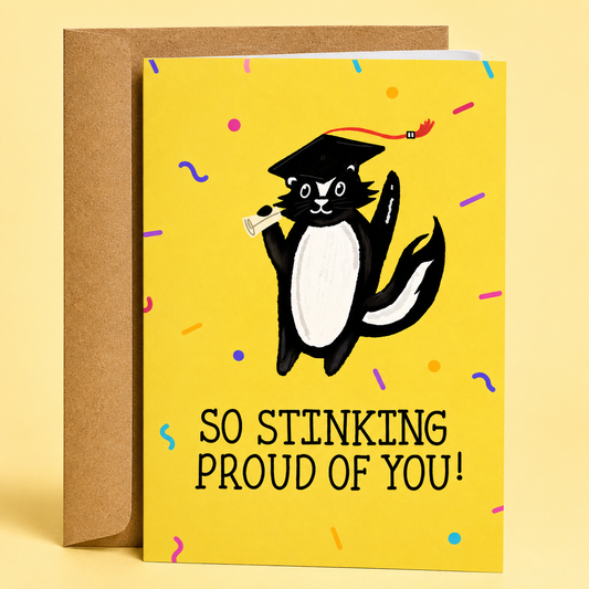 Sleazy Greetings graduation congratulations card featuring a black and white skunk wearing a graduation cap and holding a diploma on a bright yellow background with confetti, reading “So Stinking Proud Of You!” and paired with a kraft envelope.