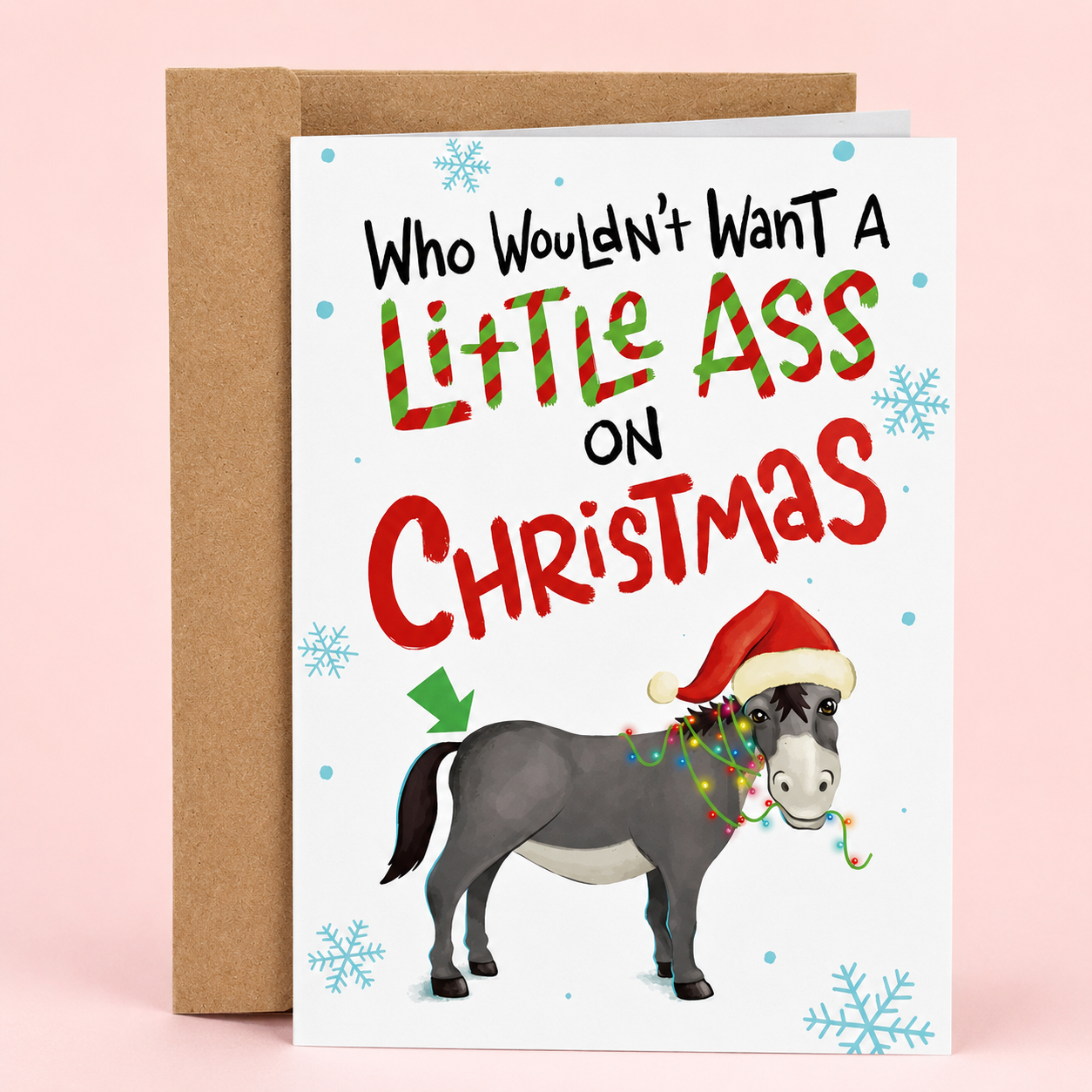 Sleazy Greetings funny Christmas card featuring the phrase ‘Who Wouldn’t Want A Little Ass On Christmas’ with a humorous donkey illustration wearing a Santa hat and Christmas lights. Pun-filled holiday greeting card with snowflake accents, playful typography, and a kraft envelope included.