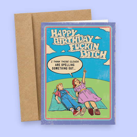 Funny vintage-style birthday card by Sleazy Greetings. Kids lying on grass spot clouds that spell “Happy Birthday Fuckin Bitch.” Bold, edgy humor. Includes kraft envelope.