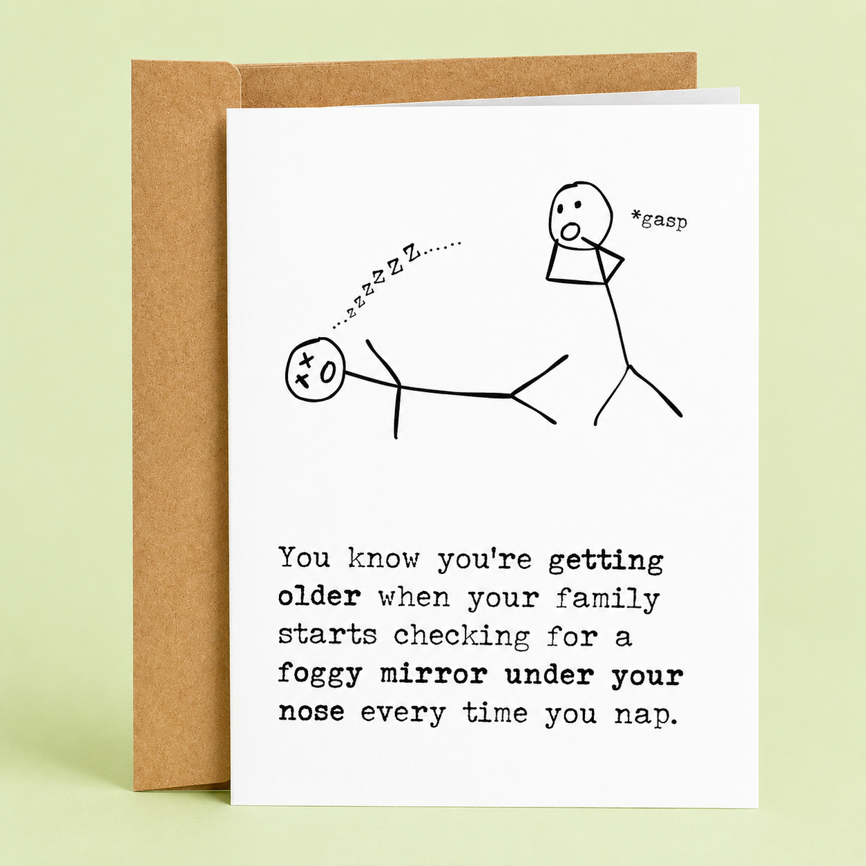 Sleazy Greetings funny birthday card featuring a stick figure cartoon with one person checking for breathing under a sleeping family member’s nose using a foggy mirror joke. Minimal black-and-white humor design on a premium white folded greeting card with kraft envelope.