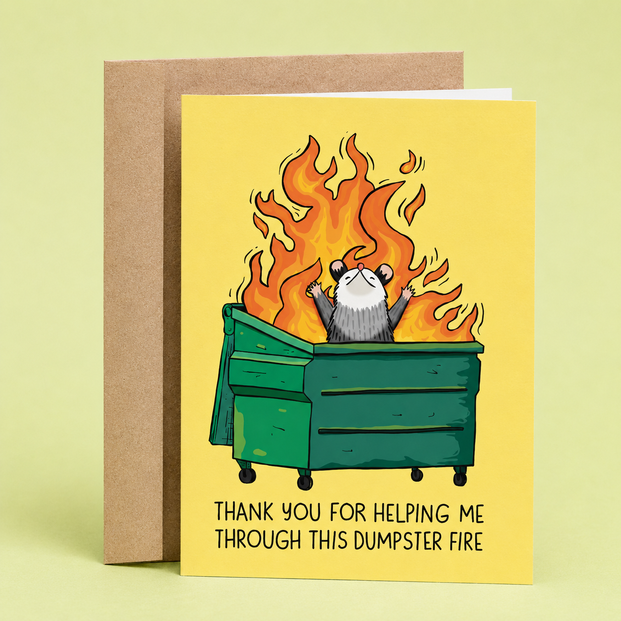 Sleazy Greetings funny thank you card featuring a possum standing in a burning dumpster with flames shooting into the air, alongside the message “Thank You for Helping Me Through This Dumpster Fire,” paired with a kraft envelope.